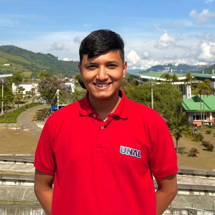 Jabes Monroy, sonriendo, con camiseta roja de la Universidad Nacional, en el campus de Manizales.